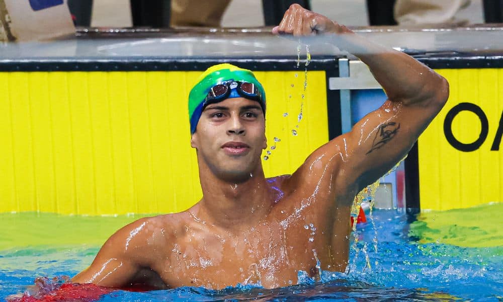 Guilherme Costa, o Cachorrão, ergue o braço para comemorar medalha
