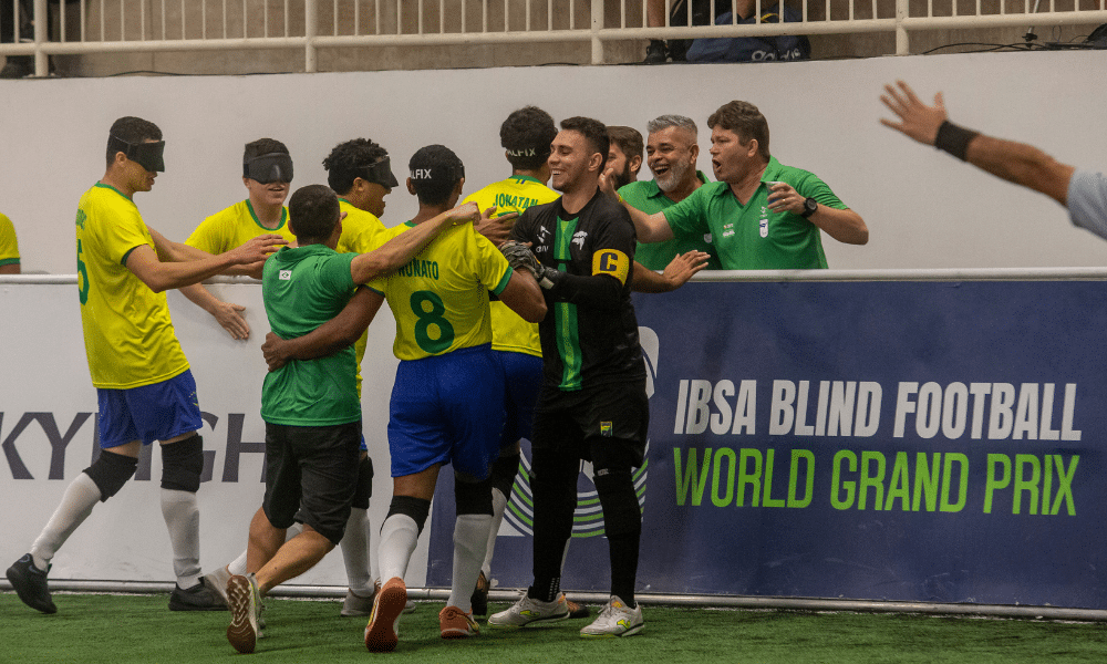 Jogadores e membros da comissão técnica se abraçam próximo à banda em comemoração a gol