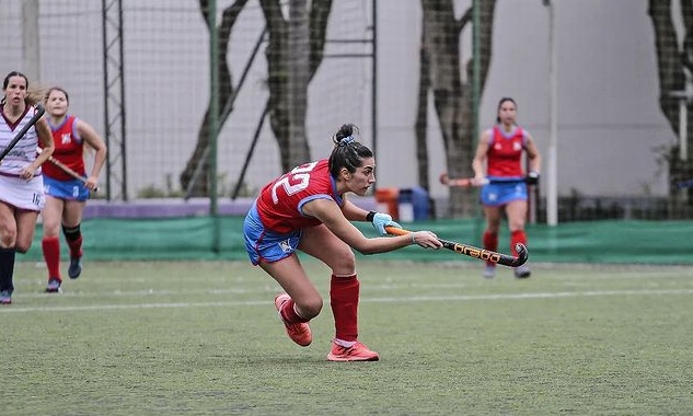 Na imagem, jogadora do Florianópolis dando uma tacada na bola de Hóquei sobre a grama.