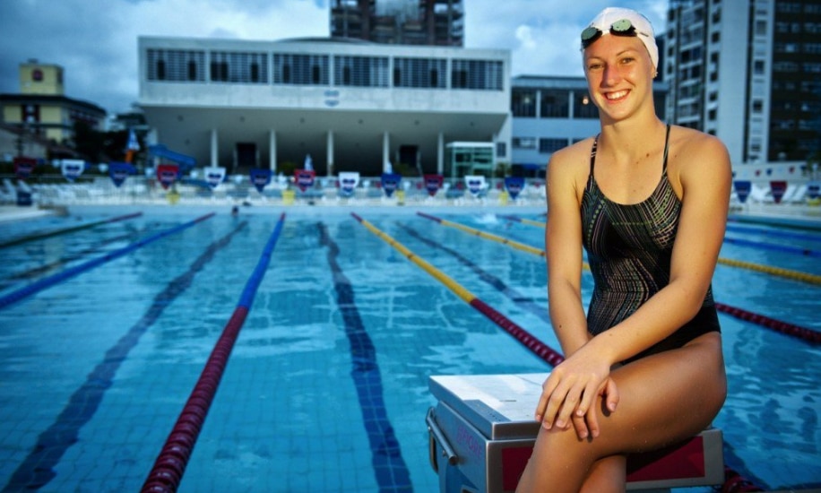 Na imagem, Graciele Herrmann sentada no bloco de partida da piscina.