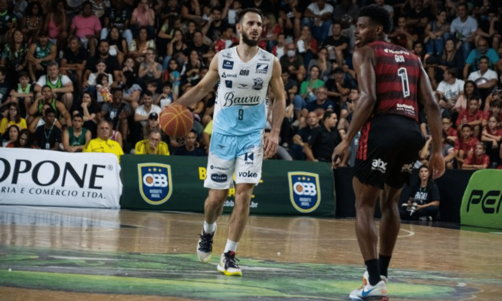 Danilo Fuzaro, do Bauru, conduz a bola enquanto é marcado por atleta do Flamengo no NBB