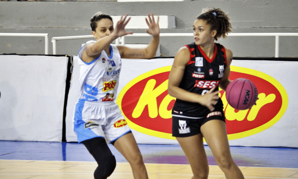 Gabriella Sossô, do Sesi Araraquara, conduz a bola marcada por atLETA DO Bax Catanduva em jogo da LBF