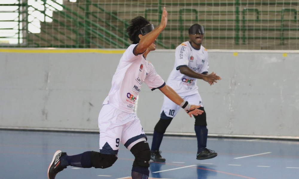 Tiago Paraná corre com os braços para cima e sorrindo durante comemoração de seu gol diante da Apadv; ao fundo, Jefinho corre batendo palmas e vibrando com gol do Maestro. Foto: Renan Cacioli/ CBDV.