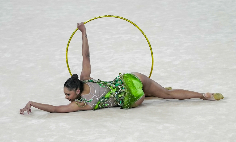 Babi Domingos, comandada por Márcia Naves, segura arco durante apresentação da ginástica rítmica