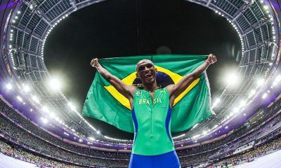 Alison dos Santos comemora com a bandeira do Brasil a conquista da medalha de bronze nos 400 m com barreiras nos Jogos Olímpicos de Paris-2024