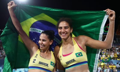 Duda e Ana Patrícia com bandeira do Brasil após ouro no vôlei de praia em Paris-2024; elas também medalharam nos Jogos Olímpicos da Juventude