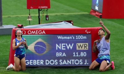 Jerusa Geber posa ao lado da placar com o recorde mundial que ela bateu nos 100 m T11 dos Jogos Paralímpicos de Paris-2024