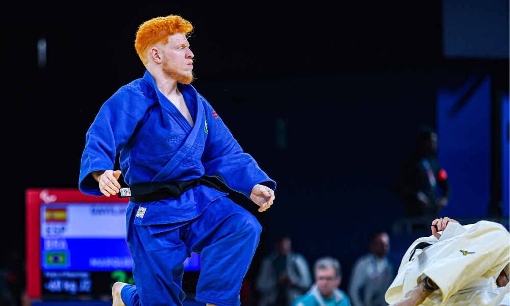 Thiego Marques, que é branco e de cabelo ruivo, está de judogi azul e está se levantando durante disputa do judô nas Paralimpíadas de Paris-2024