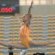 Brenda Faria no campeonato sul-americano de ginástica artística. Ela executa um salto longo e veste um collant laranja